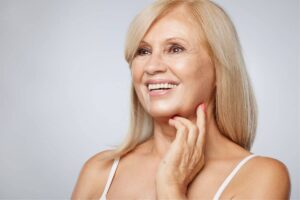 Happy mature woman with smooth, rejuvenated skin after a facelift, highlighting natural and youthful results.
