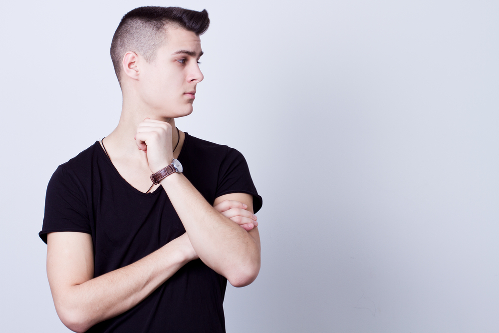 Teen boy in black shirt looking sideways, symbolizing the decision-making process for early rhinoplasty