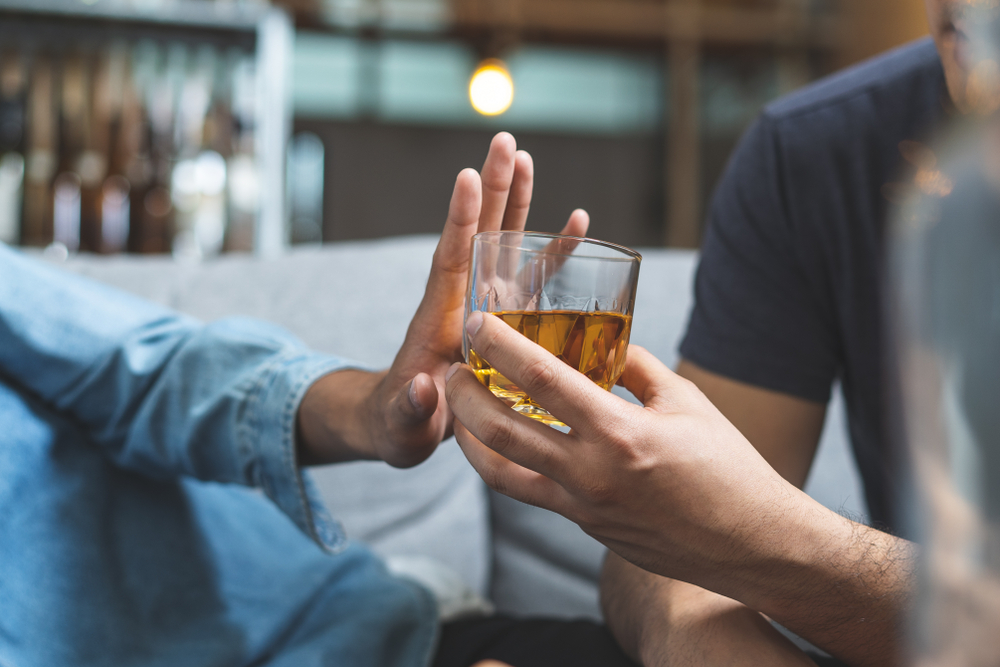 Person refusing a glass of alcohol, symbolizing the importance of avoiding alcohol before facelift surgery.