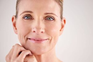 Middle-aged woman with smooth skin and minimal signs of facelift scarring.