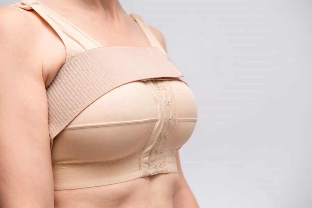 Patient wearing a compression garment during breast augmentation recovery to support healing and implant settling.