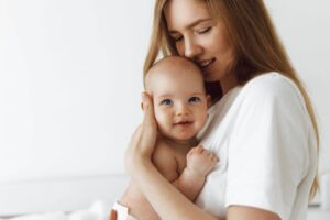 Mother holding baby while discussing breastfeeding after breast augmentation and how implants may affect nursing.
